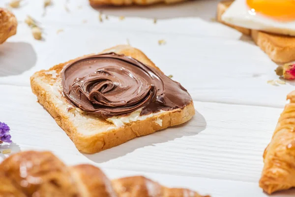 Focalizzazione selettiva di dolce pane tostato con crema di cioccolato su bianco — Foto stock