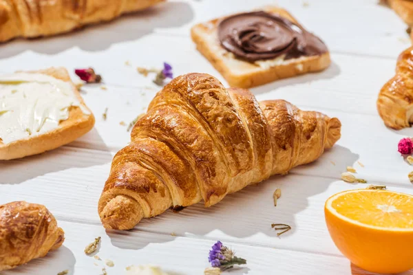Focalizzazione selettiva di croissant vicino a pane tostato con crema di cioccolato su bianco — Foto stock