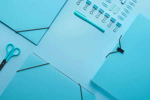 Flache Papiermappen und diverse Schreibwaren isoliert auf blauem Grund — Stockfoto