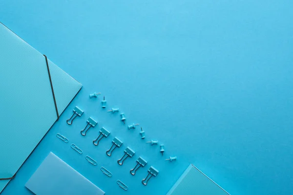 Плоский шар паперового зв'язувача і різні канцелярські товари ізольовані на синьому з копіювальним простором — стокове фото