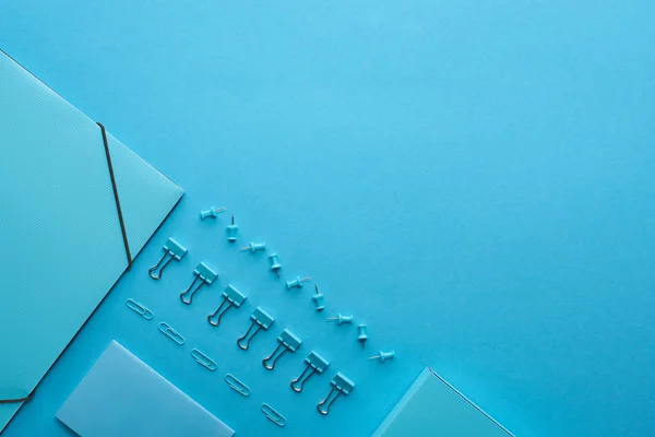 Flat lay of paper binder and various stationery isolated on blue with copy space — Stock Photo