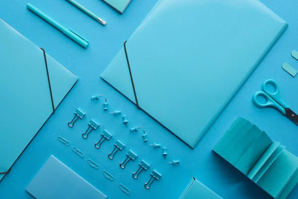 Flat lay of paper binders, paper clips and various stationery isolated on blue — Stock Photo