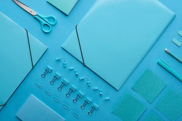 Plano de aglutinantes de papel, clips de papel y varios artículos de papelería aislados en azul - foto de stock