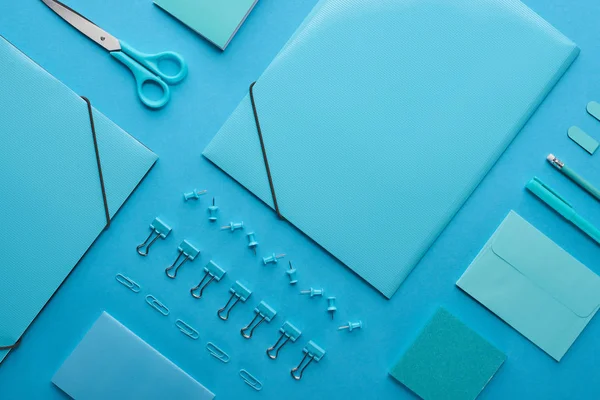 Плоская укладка бумажных связок и организованных канцелярских принадлежностей, изолированных на голубом — стоковое фото