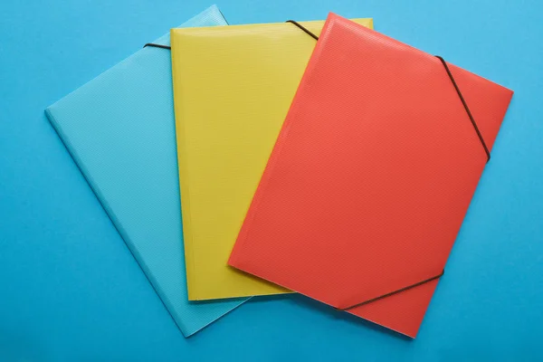 Vista dall'alto di raccoglitori di carta rossi, blu e gialli isolati su blu — Foto stock