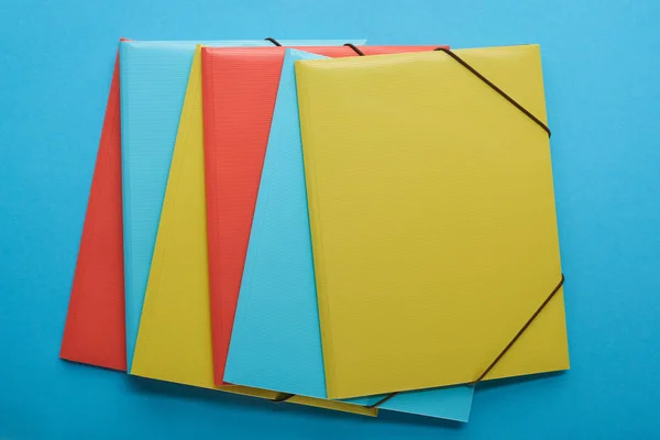 Вид зверху розташованих червоних, синіх і жовтих паперових зв'язувачів — стокове фото