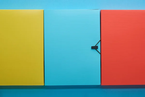 Vue de dessus des dossiers en papier coloré de bureau sur bleu — Photo de stock