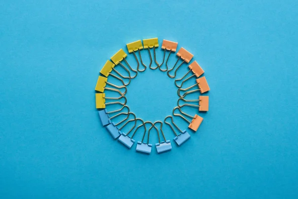 Top view of paper clips arranged in round shape isolated on blue — Stock Photo