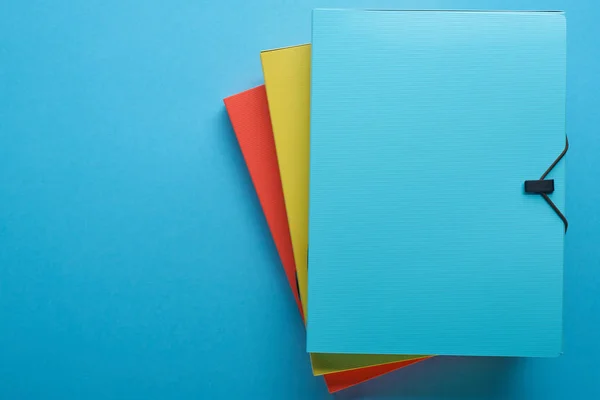Vista superior de aglutinantes de papel de colores aislados en azul con espacio de copia — Stock Photo