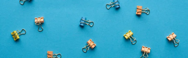 Tiro panorâmico de clipes de papel coloridos isolados em azul — Fotografia de Stock