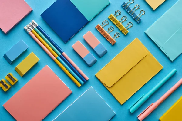 Vista superior de cadernos e artigos de papelaria coloridos arranjados isolados em azul — Fotografia de Stock