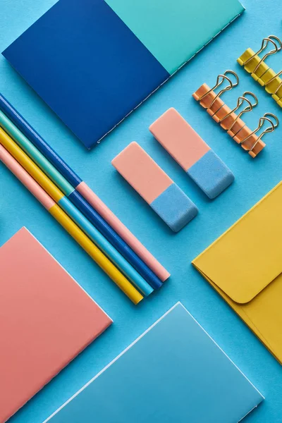 Vista superior de cuadernos y papelería de colores aislados en azul - foto de stock