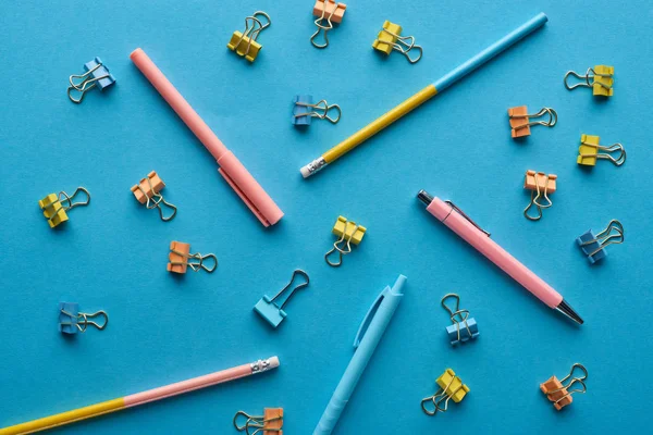Top view of pens, pencils and paper clips isolated on blue — Stock Photo