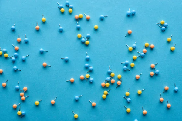 Vue de dessus des broches de poussée dispersées colorées isolées sur bleu — Photo de stock