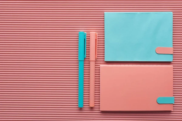Top view of arranged pens and notebooks on textured pink with copy space — Stock Photo