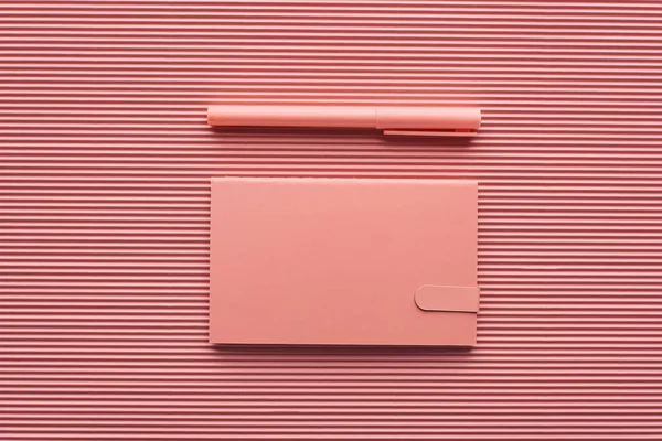 Vista superior da caneta e bloco de notas em rosa texturizado — Fotografia de Stock