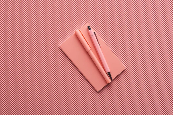 Minimalistic background with pens and notebook on textured pink — Stock Photo
