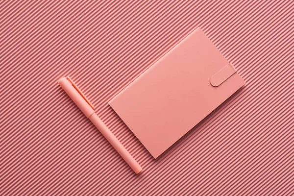 Vue du dessus du stylo et du cahier sur le rose texturé — Photo de stock