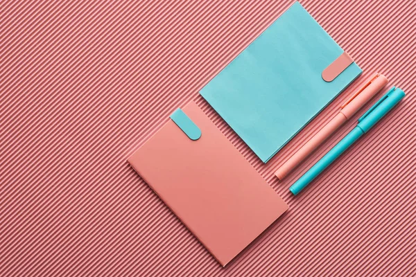 Top view of pens and notebooks on textured pink — Stock Photo