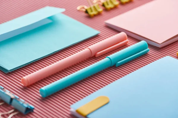 Close up of pens and colorful notebooks on pink — Stock Photo