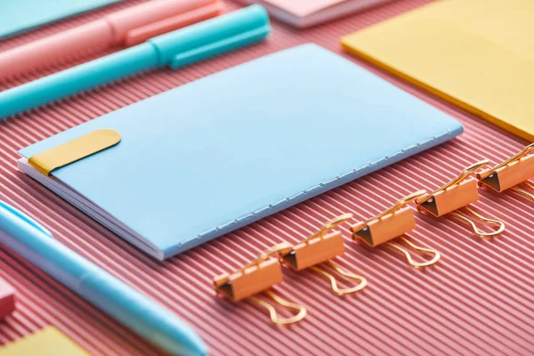 Foyer sélectif de bloc-notes, trombones et fournitures de papeterie colorées sur rose — Photo de stock