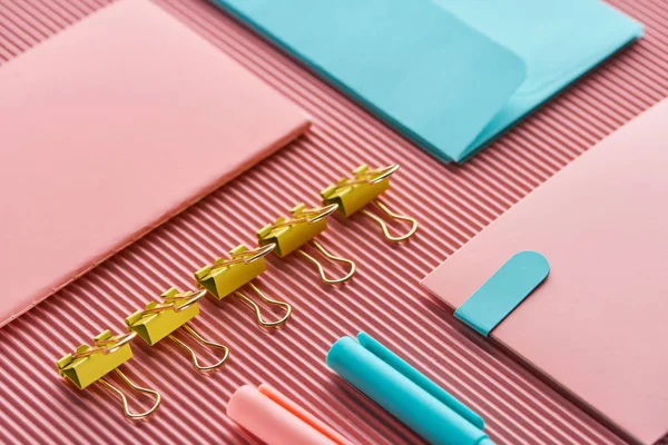 Carnet, trombones et fournitures de papeterie colorées sur rose — Photo de stock