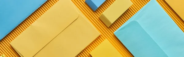 Panoramic shot of colorful envelopes and erasers on yellow — Stock Photo