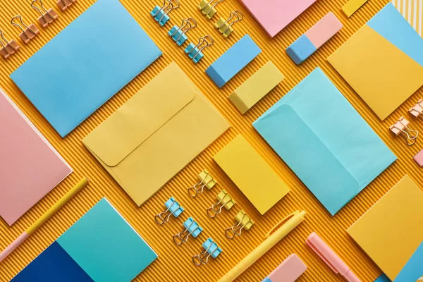 Плоская раскладка разноцветных канцелярских принадлежностей для офиса на желтом — стоковое фото