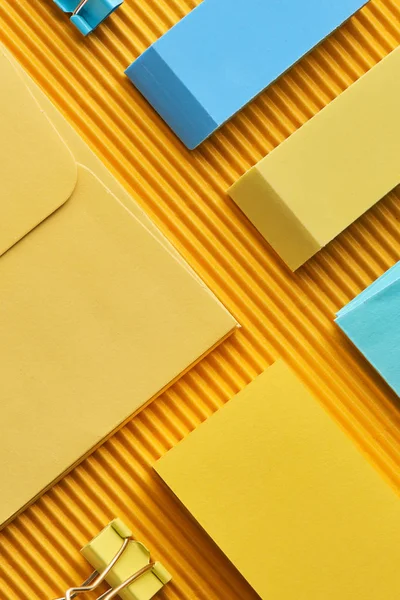 Vue du haut des notes collantes, enveloppe et gommes sur jaune — Photo de stock