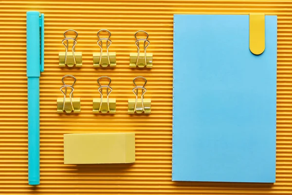 Top view of pen, notebook and colorful arranged office stationery supplies on yellow — Stock Photo