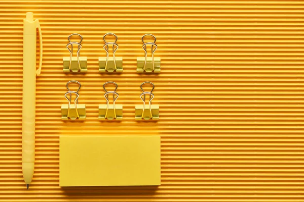 Top view of pen, paper clips and colorful arranged office stationery supplies on yellow — Stock Photo