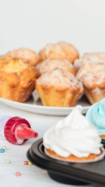 Leckere Muffins auf Teller und Cupcakes in Cupcake-Tablett isoliert auf weiß — Stockfoto
