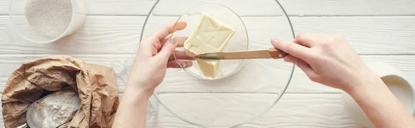 Plan panoramique de femme coupant beurre dans un bol sur la table avec des ingrédients — Photo de stock