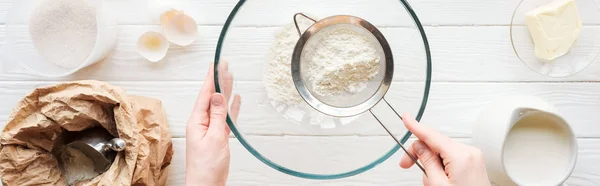 Colpo panoramico di donna setacciando la farina in ciotola sul tavolo con gli ingredienti — Foto stock