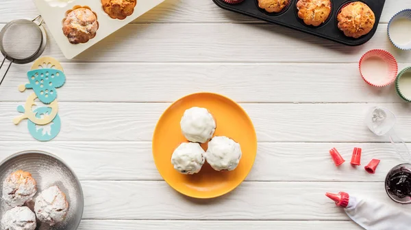 Vue de dessus de délicieux cupcakes et outils de cuisson sur table en bois — Photo de stock