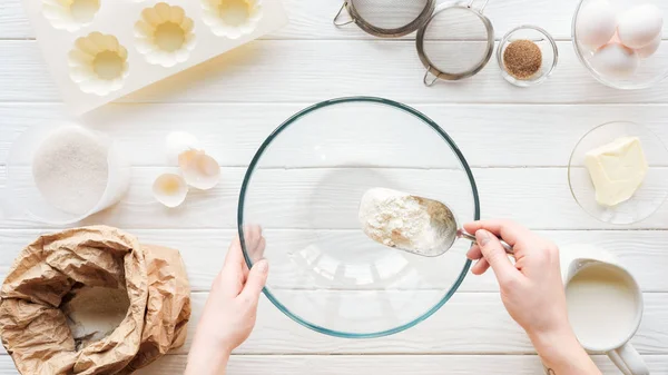 Abgeschnittene Ansicht einer Frau mit einer Schaufel Mehl in eine Schüssel geben, während sie auf dem Tisch kocht — Stockfoto