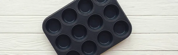 Panoramic shot of metal muffin tray on white wooden table — Stock Photo