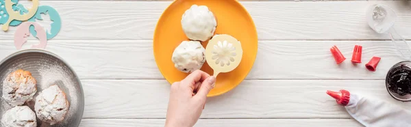 Panoramic shot of woman decorating cupcakes on plate with baking stencil — Stock Photo