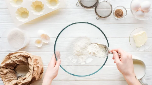 Vista cortada da mulher com colher colocando farinha na tigela enquanto cozinha na mesa — Fotografia de Stock