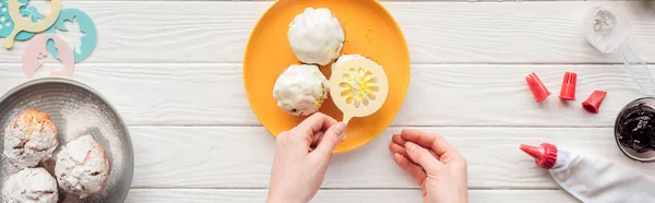 Plan panoramique de femme décoration cupcakes avec pochoir à pâtisserie sur table blanche — Photo de stock