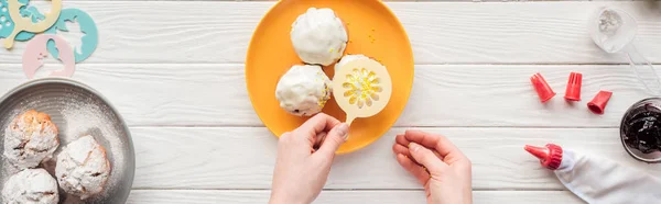 Panoramic shot of woman decorating cupcakes with baking stencil on white table — Stock Photo