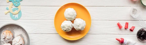 Tiro panorâmico de deliciosos cupcakes e ferramentas de cozimento na mesa de madeira branca — Fotografia de Stock