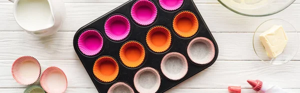 Panoramic shot muffin mold, butter, paper forms and icing bag on table — Stock Photo