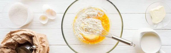 Panoramic shot of bowl with dough, kitchen utensils and ingredients on table — Stock Photo