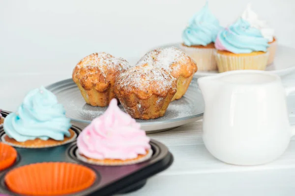 Deliciosos panecillos y cupcakes con glaseado colorido aislado en gris - foto de stock