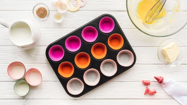 Top view of muffin mold, kitchen utensils and ingredients on table — Stock Photo