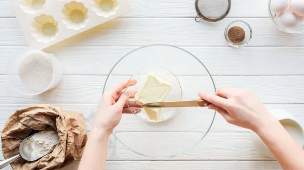 Vista ritagliata di donna che taglia burro in ciotola sul tavolo con ingredienti — Foto stock