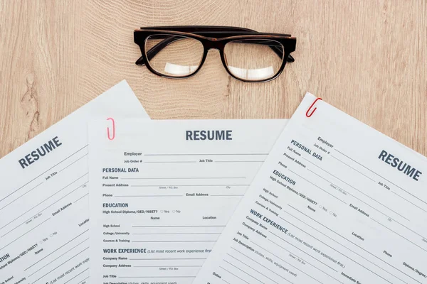 Vue du dessus des modèles de CV imprimés et des verres sur la table en bois — Photo de stock