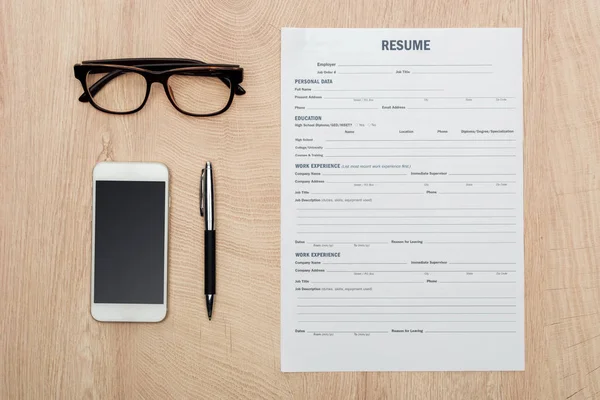 Plano con gafas, bolígrafo, smartphone con pantalla en blanco y plantilla de CV en la superficie de madera - foto de stock