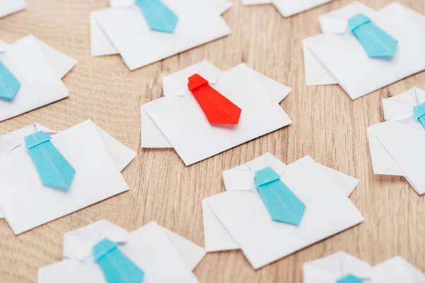 Origami white shirts with blue ties with one red on wooden table — Stock Photo